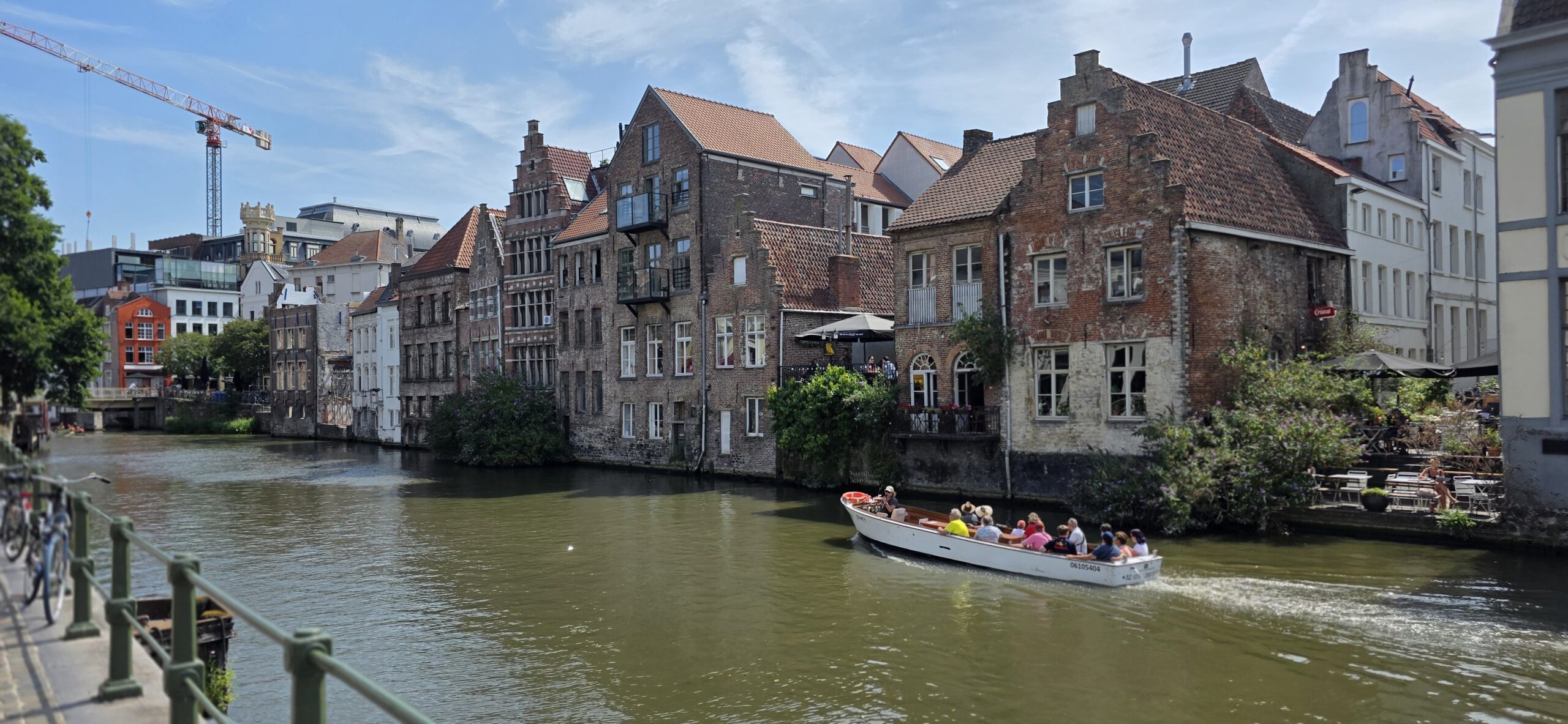 Medieval guild houses lining a canal in Ghent with a tour boat passing